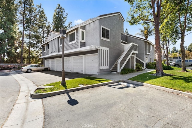 view of front facade featuring stairs, an attached garage, stucco siding, and driveway