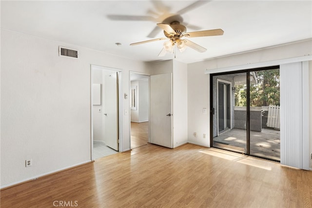 spare room with baseboards, ceiling fan, visible vents, and wood finished floors
