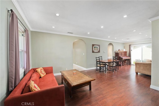 living area with baseboards, wood finished floors, arched walkways, and ornamental molding