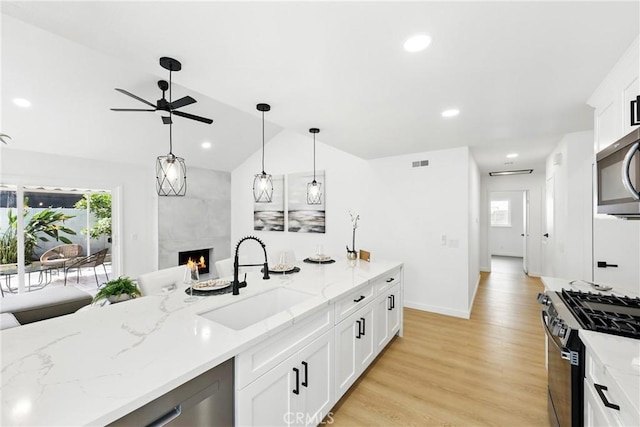 13538 Darvalle St, Cerritos, CA 90703 - kitchen with a sink, vaulted ceiling, a ceiling fan, a fireplace, and appliances with stainless steel finishes