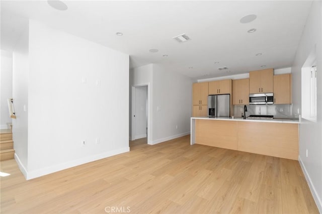 kitchen with visible vents, appliances with stainless steel finishes, a peninsula, light wood finished floors, and light brown cabinets