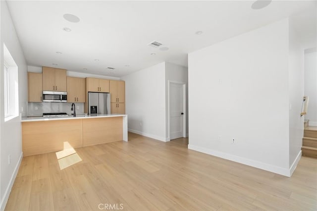 kitchen with baseboards, appliances with stainless steel finishes, light wood-type flooring, and light brown cabinets