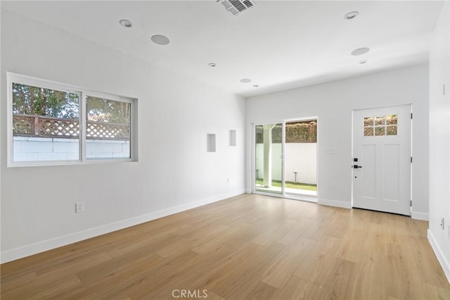 unfurnished living room featuring a healthy amount of sunlight, baseboards, light wood-type flooring, and visible vents