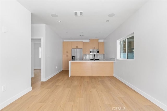 kitchen with visible vents, appliances with stainless steel finishes, light wood-type flooring, a peninsula, and light brown cabinets