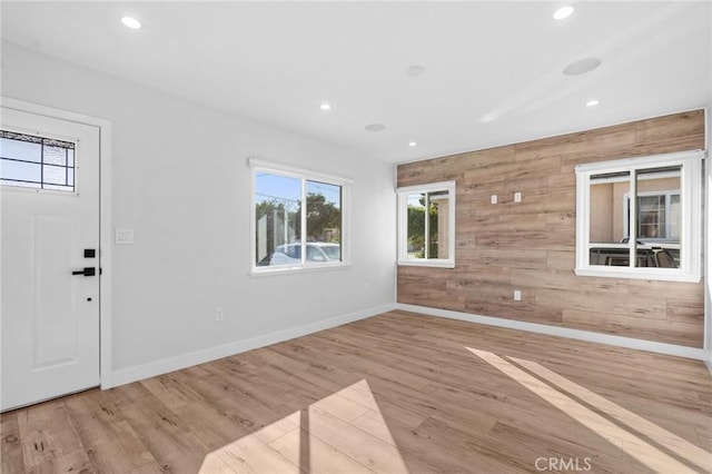 foyer with recessed lighting, plenty of natural light, wood walls, and wood finished floors
