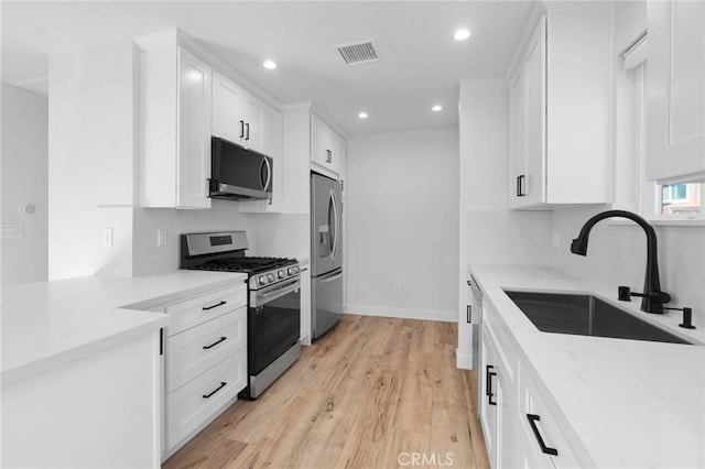 kitchen featuring visible vents, recessed lighting, white cabinets, a sink, and stainless steel appliances
