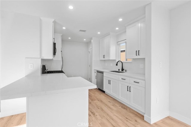 kitchen with a sink, light countertops, a peninsula, stainless steel appliances, and visible vents