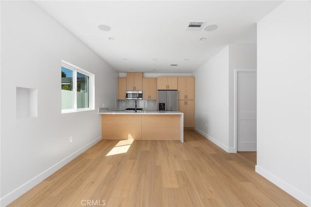 kitchen featuring light brown cabinetry, stainless steel appliances, visible vents, and light wood-style flooring