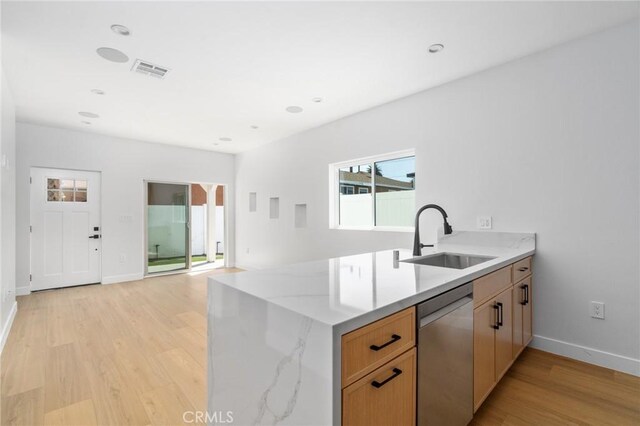 kitchen featuring light stone counters, a sink, light wood-style floors, baseboards, and stainless steel dishwasher