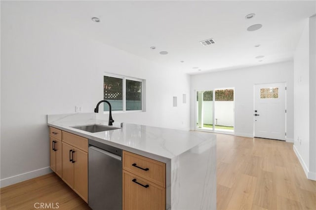 kitchen featuring stainless steel dishwasher, light stone countertops, a sink, light wood finished floors, and a peninsula