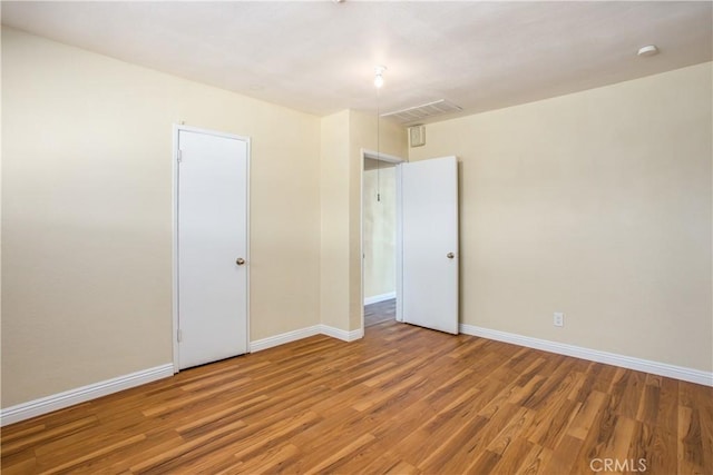 empty room featuring visible vents, baseboards, and wood finished floors
