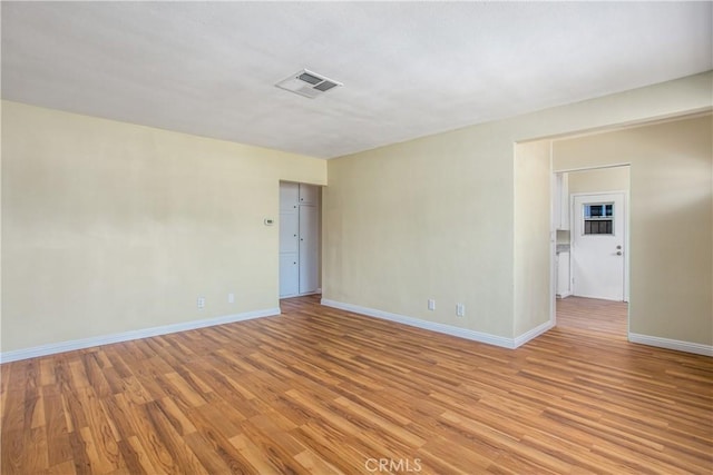 unfurnished room with light wood-type flooring, baseboards, and visible vents