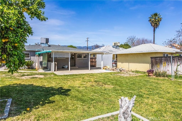 back of house with fence, a patio, a lawn, and stucco siding
