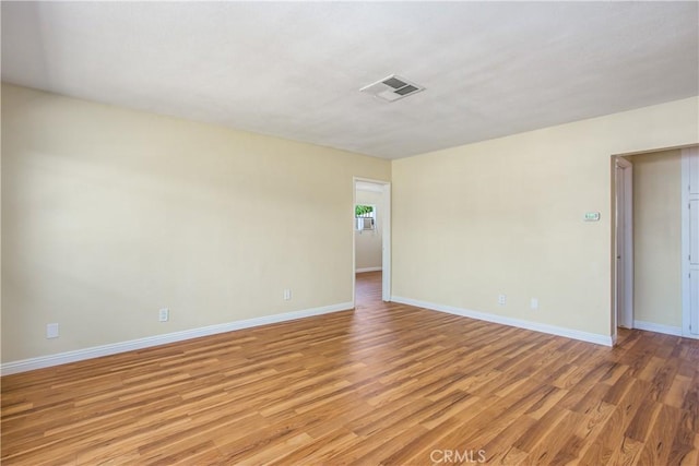 spare room featuring visible vents, light wood-style flooring, and baseboards