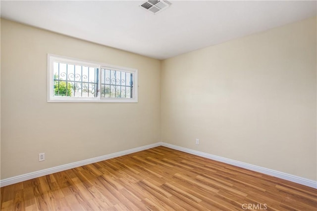 empty room featuring visible vents, baseboards, and light wood finished floors