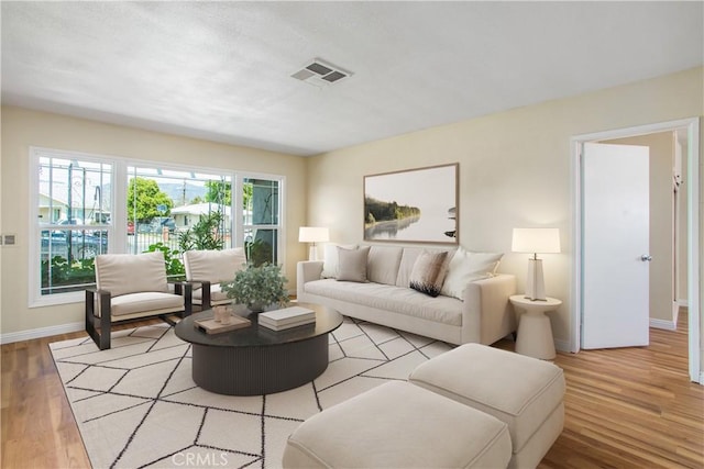 living area with visible vents, baseboards, and wood finished floors
