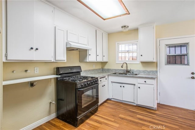 kitchen with white cabinets, under cabinet range hood, a sink, and gas stove