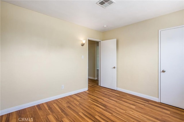 unfurnished room with wood finished floors, baseboards, and visible vents