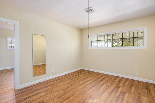 empty room with visible vents, baseboards, and wood finished floors