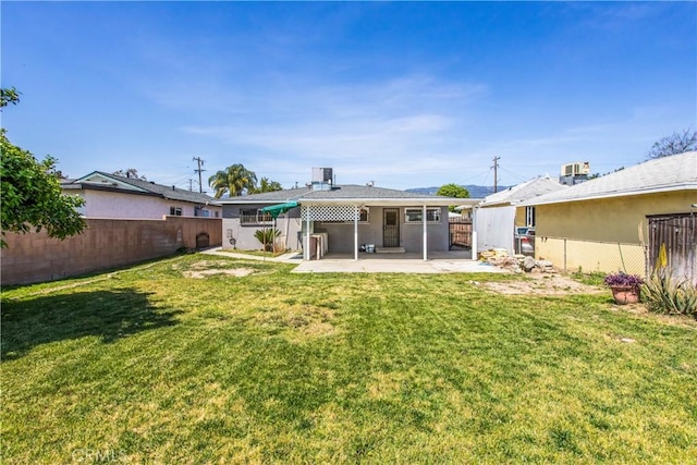 rear view of house with a patio area, a fenced backyard, cooling unit, and a yard
