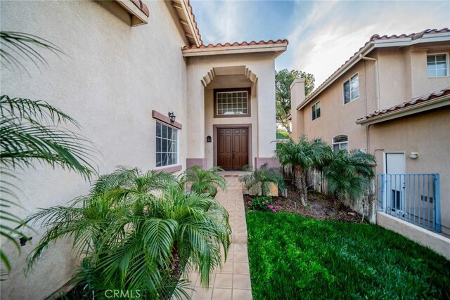 property entrance with a tile roof and stucco siding