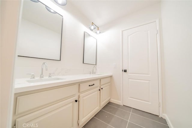 bathroom featuring tile patterned flooring, double vanity, baseboards, and a sink