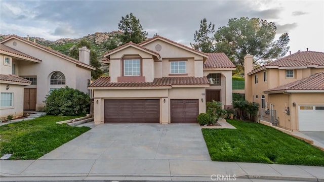 mediterranean / spanish house featuring stucco siding, driveway, an attached garage, a front yard, and a tiled roof