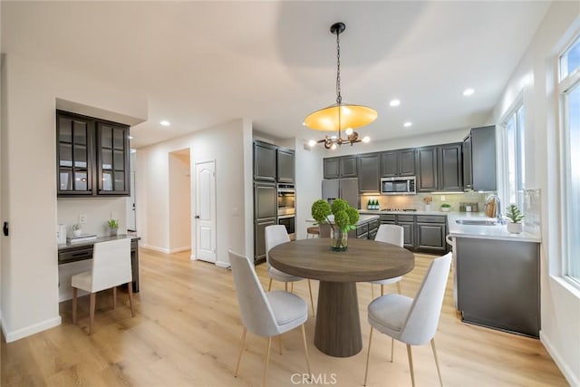dining space with light wood-style flooring, recessed lighting, an inviting chandelier, and baseboards