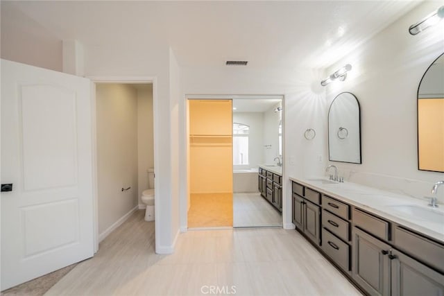 full bathroom featuring double vanity, a sink, and toilet
