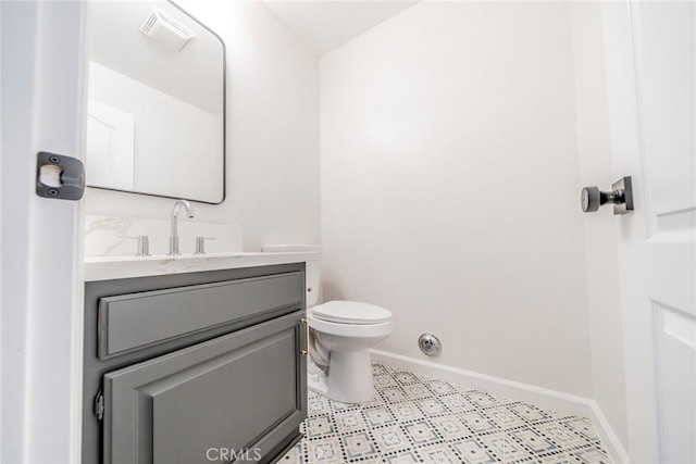 half bath with visible vents, toilet, vanity, and baseboards