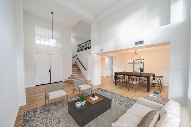 living area featuring visible vents, wood finished floors, stairs, baseboards, and a notable chandelier
