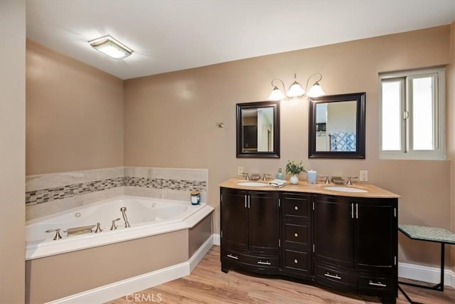 full bathroom featuring a bath, double vanity, a sink, and wood finished floors