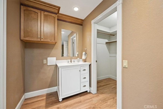 bathroom with baseboards, a textured wall, wood finished floors, and vanity