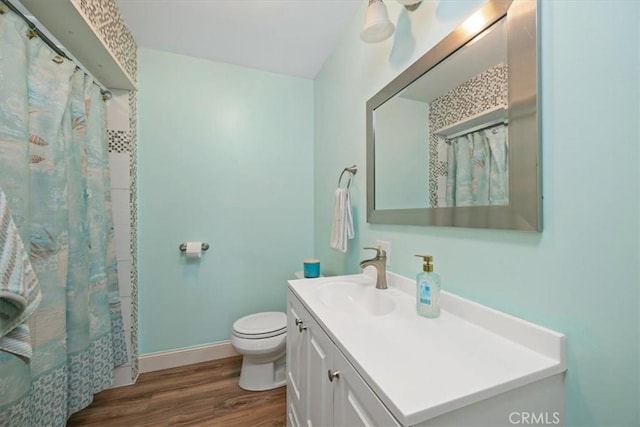 bathroom featuring baseboards, toilet, wood finished floors, vanity, and a shower with curtain