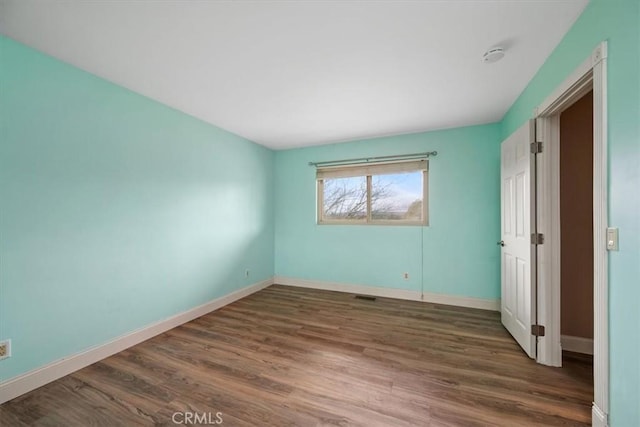 unfurnished bedroom featuring baseboards, visible vents, and wood finished floors