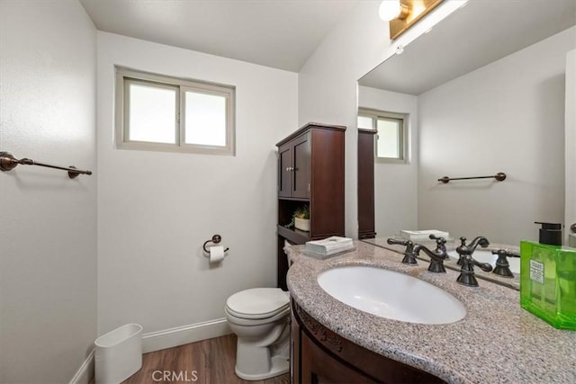 half bathroom featuring toilet, wood finished floors, baseboards, and vanity