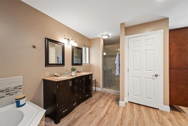 full bath featuring a sink, a bath, a stall shower, and wood finished floors