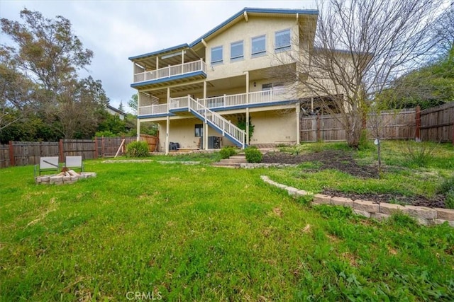 back of property featuring a fenced backyard, stairs, stucco siding, and a yard