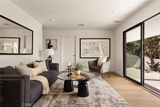 living room with light wood finished floors, visible vents, and recessed lighting