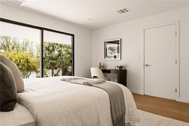 bedroom with wood finished floors, baseboards, and visible vents