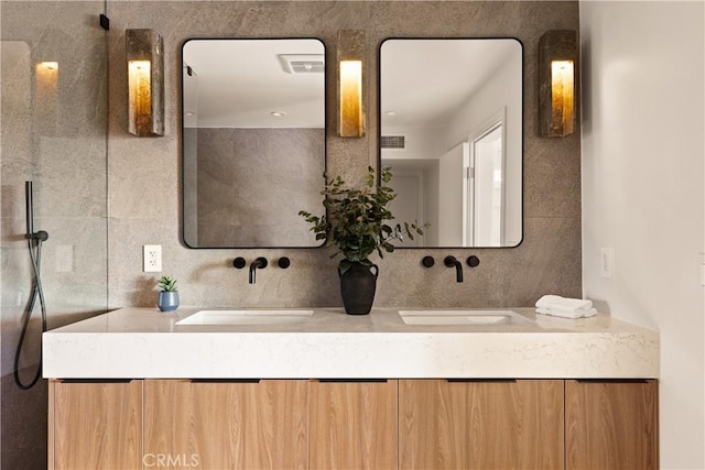 full bathroom with a sink, visible vents, tile walls, and double vanity