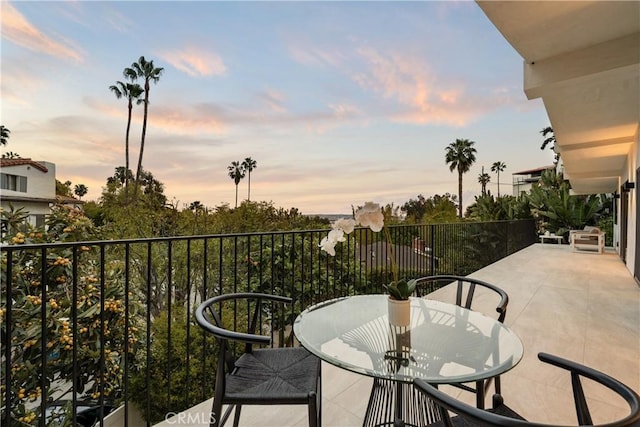 balcony at dusk featuring outdoor dining space