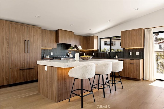 kitchen with brown cabinets, a breakfast bar, a kitchen island, and plenty of natural light