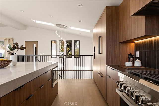 kitchen with light wood-style flooring, stainless steel range, modern cabinets, and vaulted ceiling