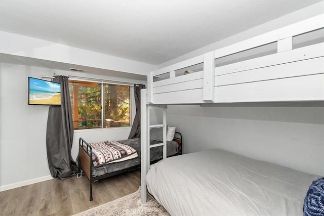 bedroom featuring baseboards, visible vents, and wood finished floors