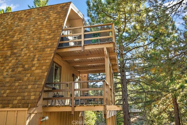 exterior space featuring a balcony and roof with shingles