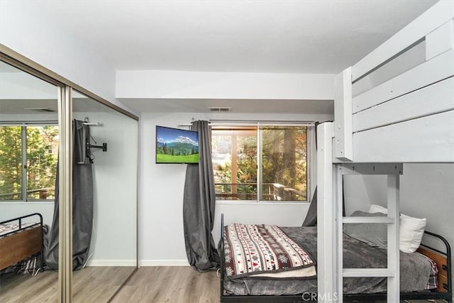 bedroom with baseboards, visible vents, and wood finished floors
