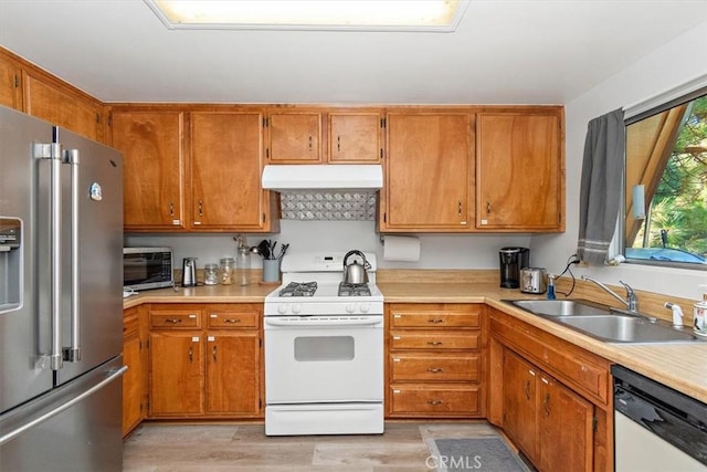 kitchen with under cabinet range hood, light countertops, a sink, and stainless steel appliances