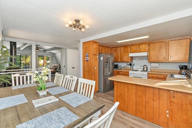 kitchen with stainless steel fridge with ice dispenser, light countertops, under cabinet range hood, and white range with gas cooktop
