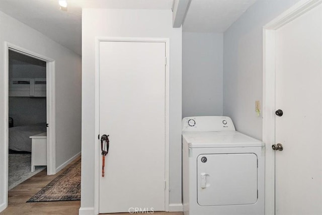 clothes washing area with baseboards, washer / clothes dryer, wood finished floors, and laundry area